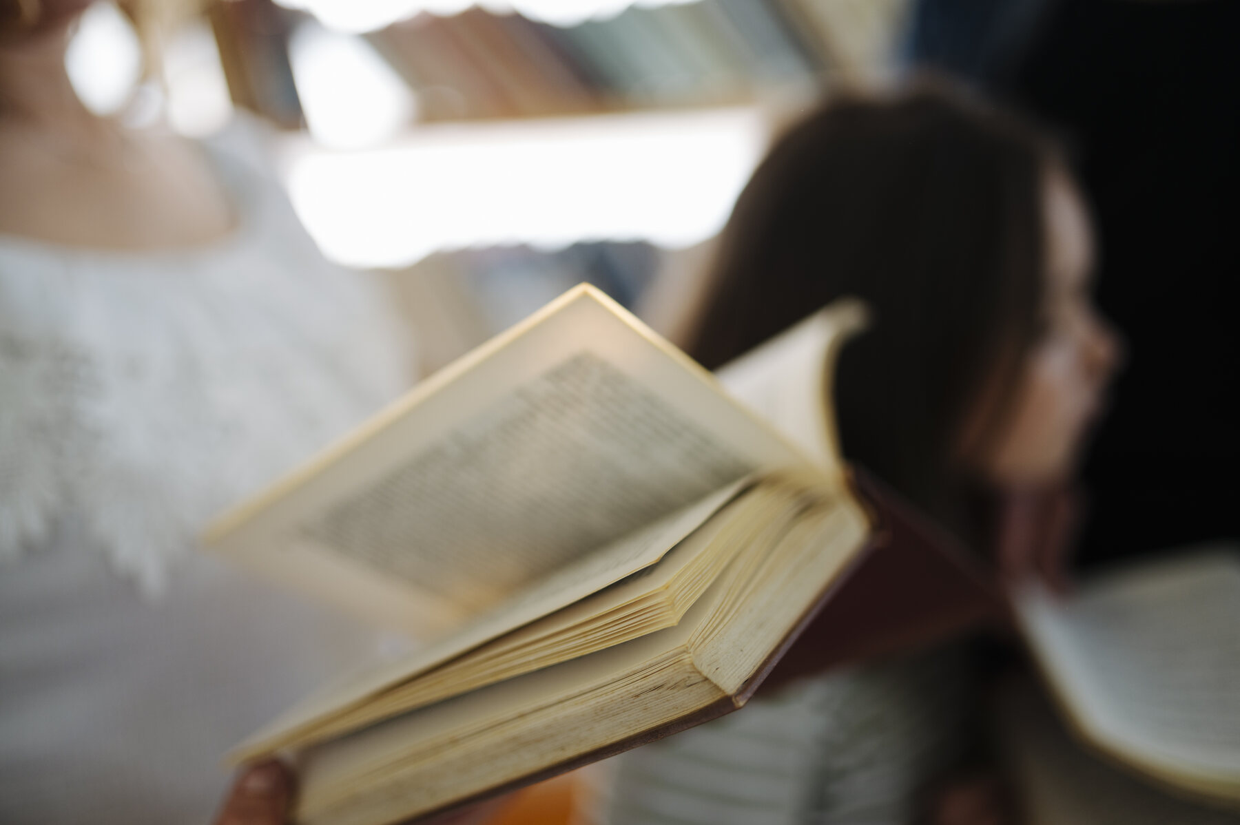 An open book held by a reader inside a library
